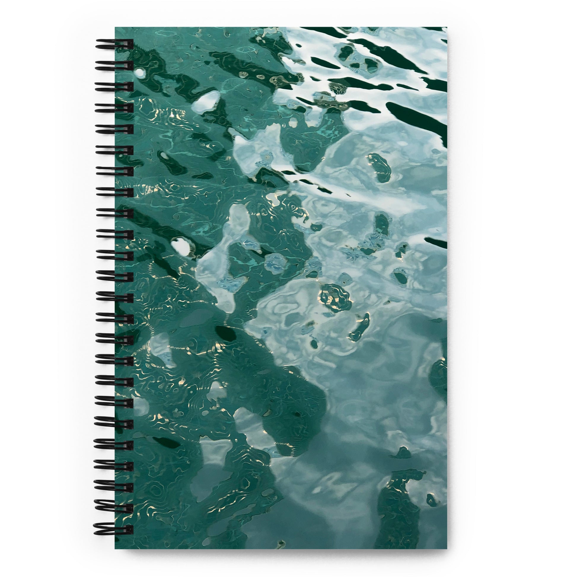 A spiral notebook with a soft-touch coating and a cover featuring a reflective, water-like pattern in shades of green and blue.